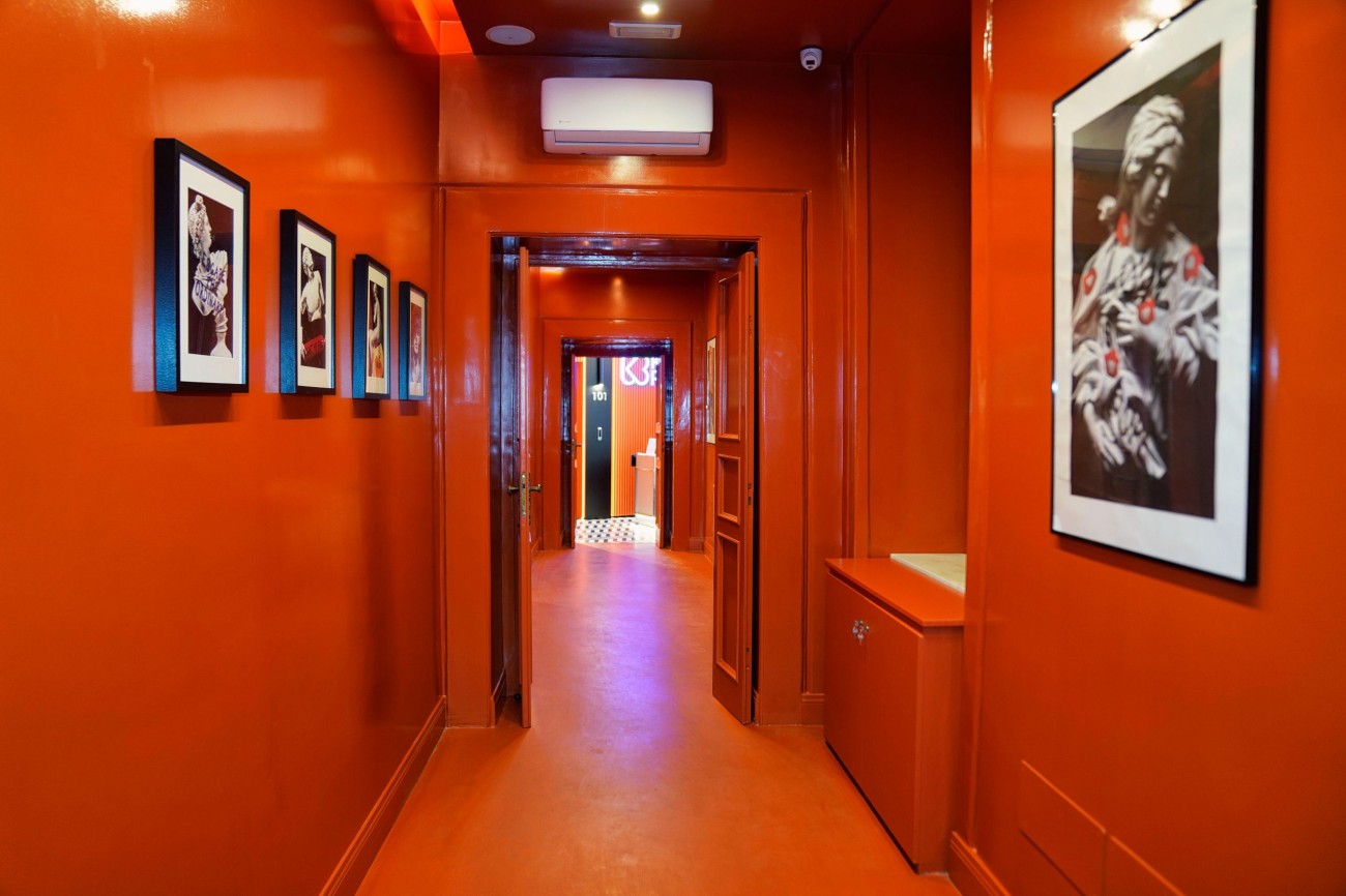 Corridoio arancio con fotografie in bianco e nero che porta alle suite
