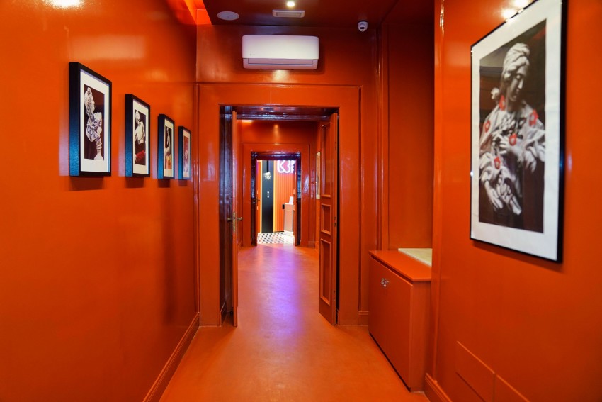 Corridoio arancio con fotografie in bianco e nero che porta alle suite